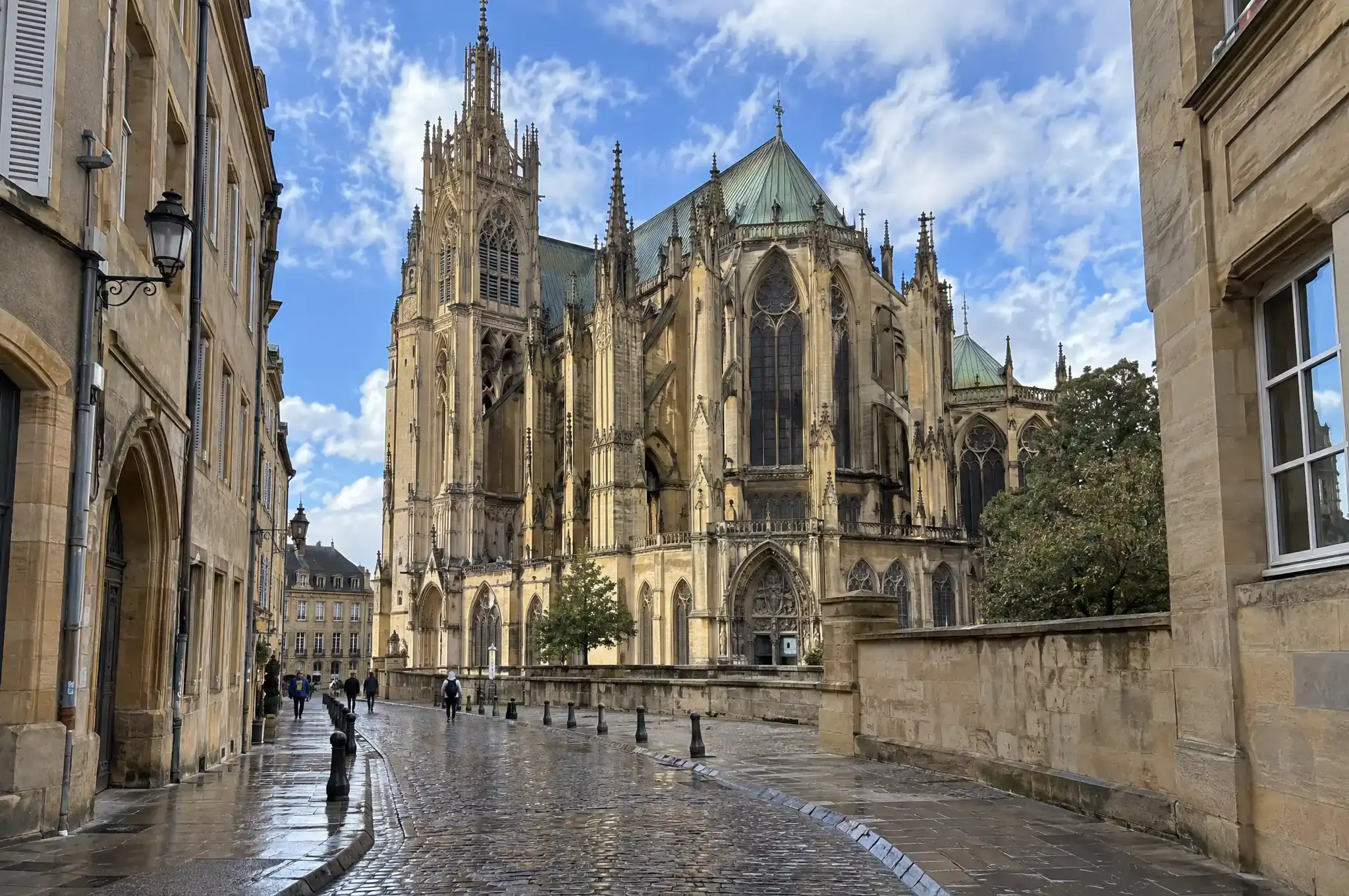 Une cathédrale gothique au bout d'une rue pavée encore mouillée, juste après une averse